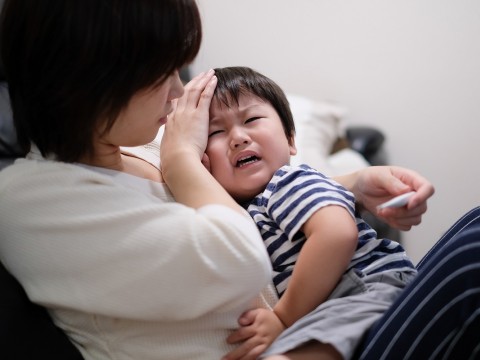 Mom comforting crying baby with fever